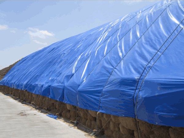Blue waterproof animal feed cover tarp on a large agricultural stack