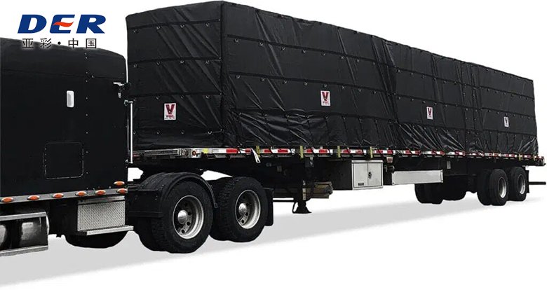 Black tarp sections covering tall rectangular freight on a flatbed truck