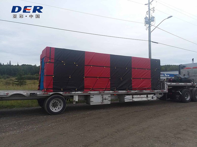 Red and black tarp sections fitted over a flatbed trailer load