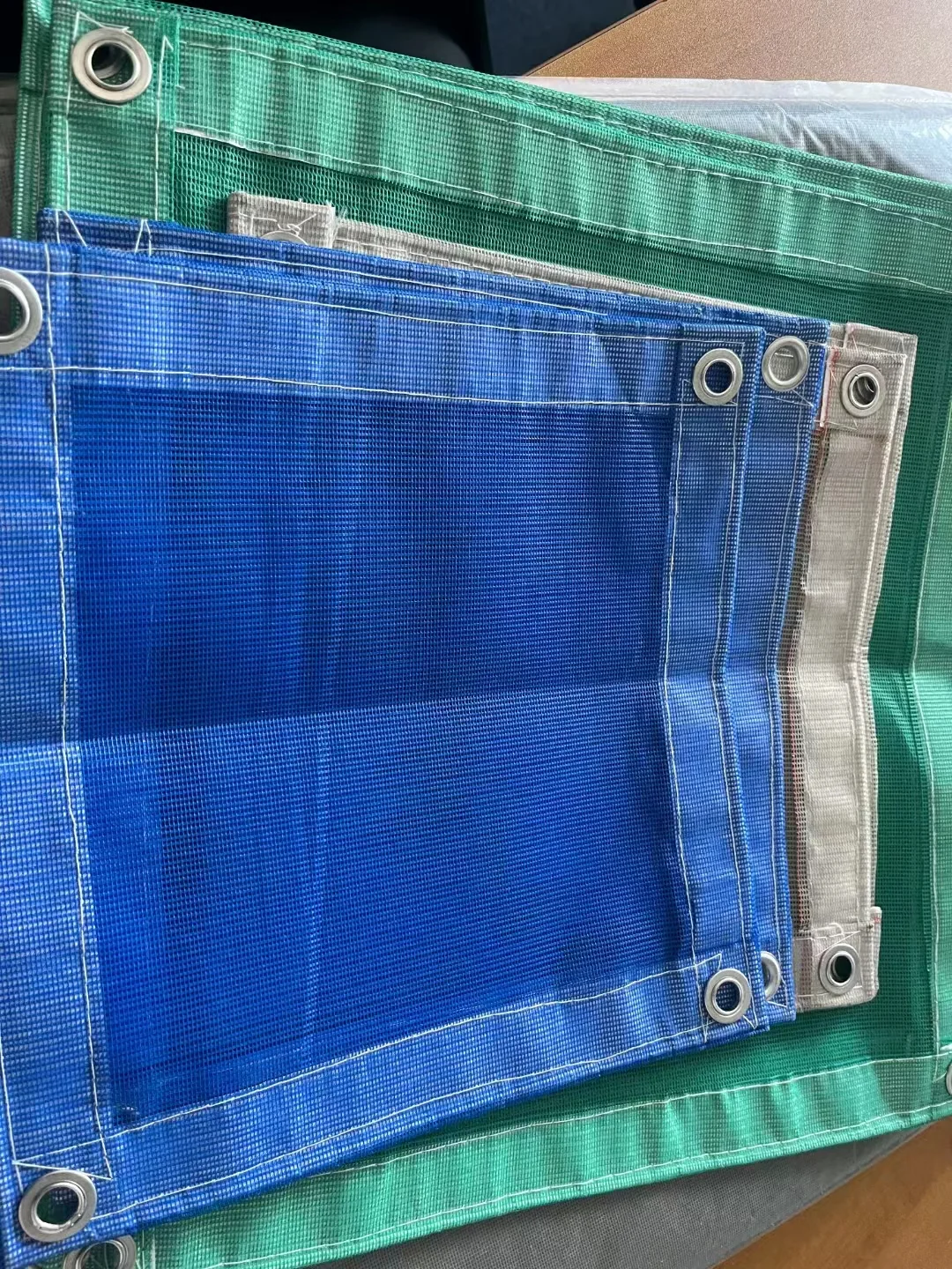 Blue green and grey DERFLEX mesh samples with reinforced edges and eyelets