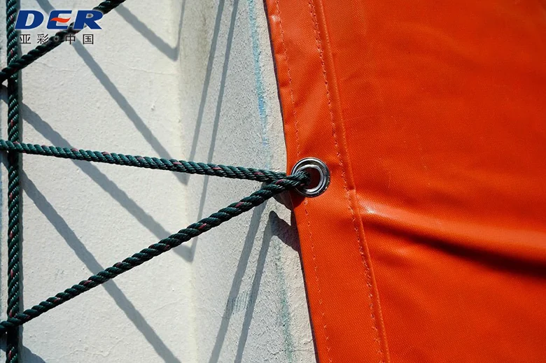 Rope passing through a metal eyelet in the reinforced stitched edge of orange coated fabric