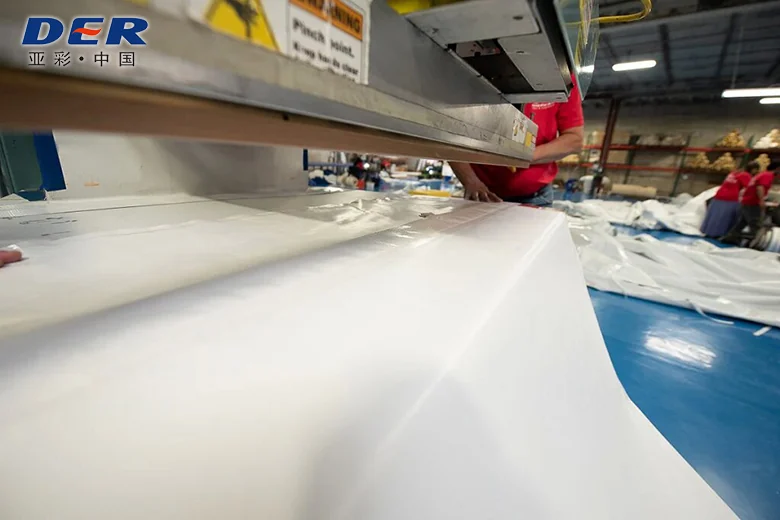 White coated fabric laid under a large fabrication press on a worktable